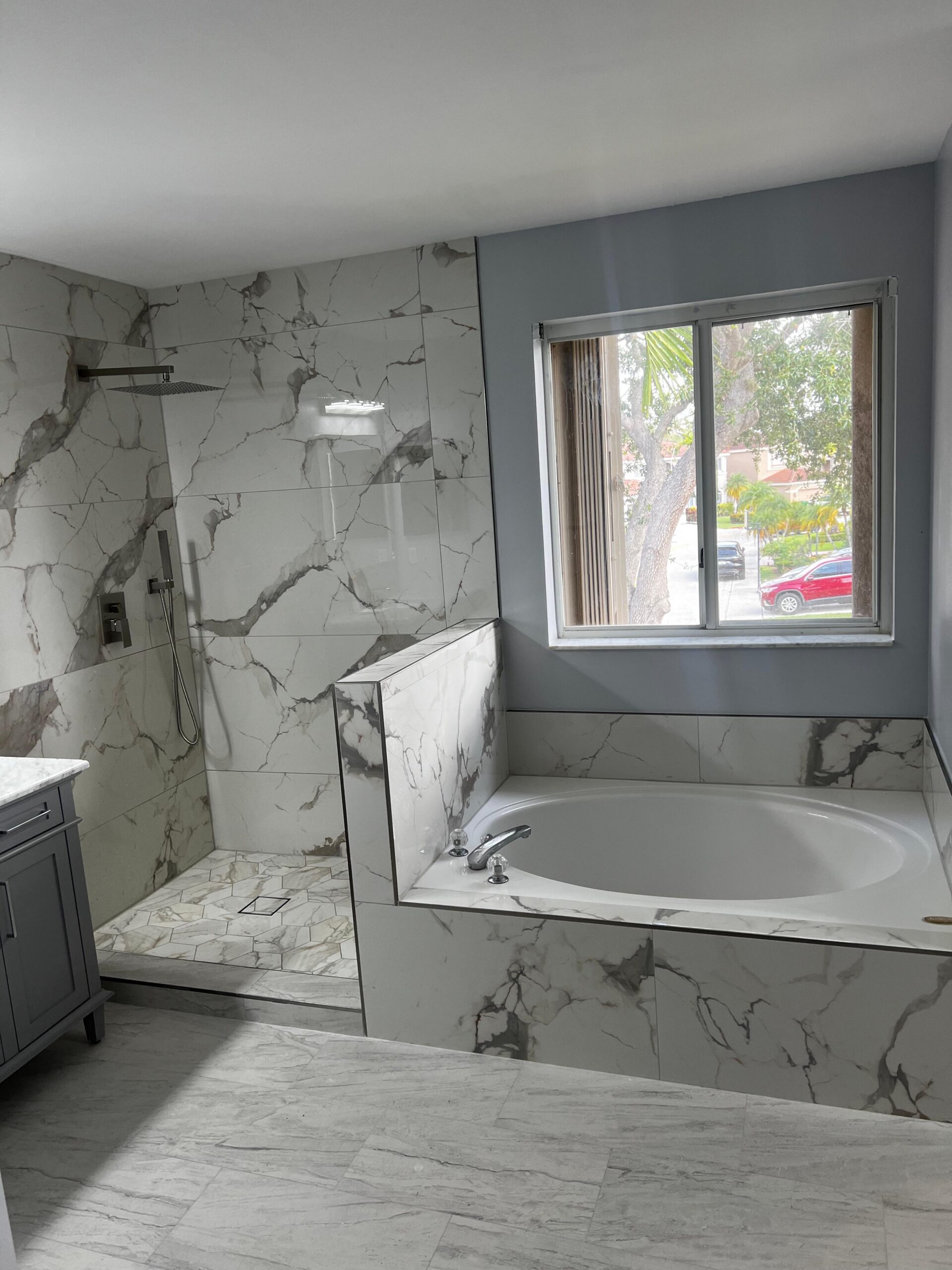 Master bathroom renovation in Hollywood Florida with freestanding tub and tile feature wall